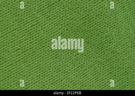 Horizontal close up of a bright green knitted wool fabric showing a neat diagonal ribbed texture on a warm winter clothing background. Stock Photo
