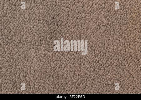 Horizontal close up of a soft brown fleece fabric with dense curly wool fibers on a cozy warm blanket or winter jacket texture surface. Stock Photo