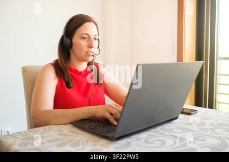 Woman working from home, talking on headset during online conference Stock Photo