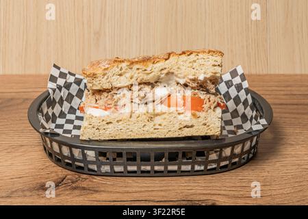 Shredded Pulled Meat Sandwich with Tomato and Mayo on Rustic Bread, Served in Checkered-Lined Basket Stock Photo