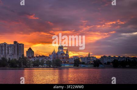 Golden sunset and Vivid afterglow over Obolon Embankment in Kyiv, Ukraine. Dramatic purple and orange clouds illuminate the skyline and church Stock Photo