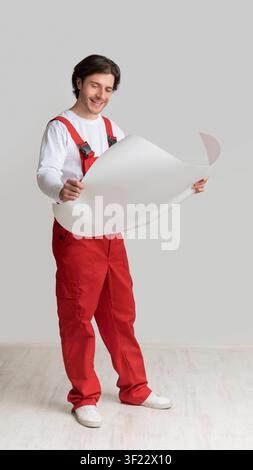 Repairment Plan. Smiling Young Engineer Holding Blueprint, Checking Project Details Stock Photo
