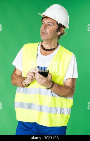 Adult man in reflective vest and hard hat using smartphone for inventory on green screen Stock Photo