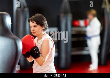 Woman practicing boxing punches on training dummy in gym Stock Photo