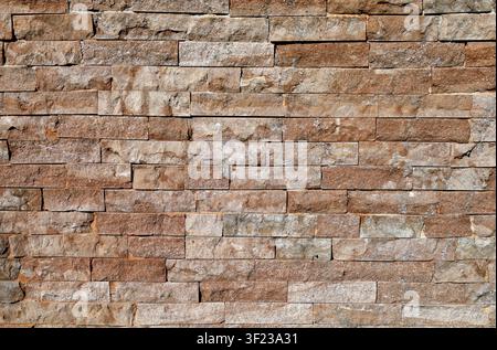Old external stone wall made of brown limestone bricks. Background and texture. Full frame. Stock Photo