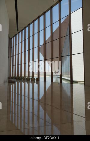 A minimalist interior space in Nizwa, Oman, featuring glass walls, strong geometric lines, reflective flooring, and a sculptural contemporary facade Stock Photo