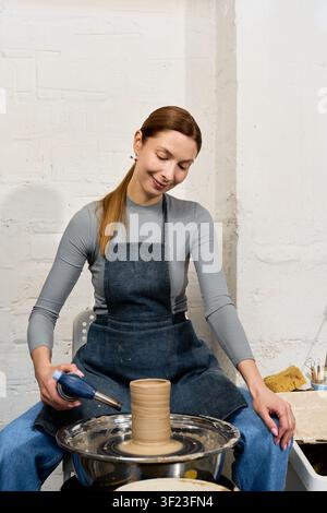 Skilled potter focuses on crafting clay forms in her warm, welcoming studio Stock Photo