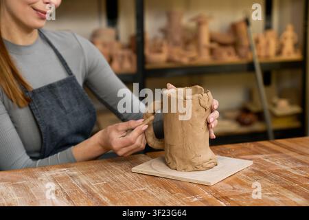 A skilled potter shapes clay into stunning earthenware while enjoying her craft Stock Photo