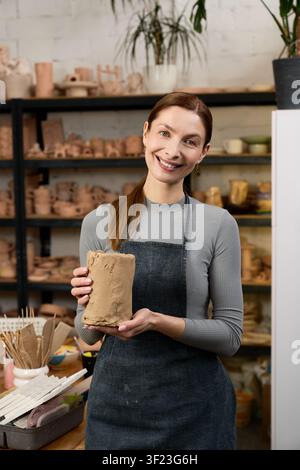 A skilled woman potter holds a piece of raw clay in her welcoming workshop Stock Photo