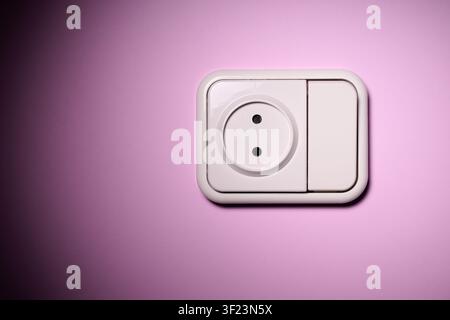 Close-up of a white switch socket, joined into a single device, on the pink wall of a house. Stock Photo