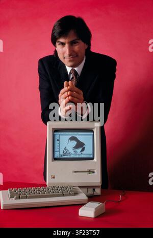 Apple co-founder Steve Jobs (1955–2011) posing with the original Macintosh computer displaying an illustration on its screen. Jobs championed the development of the Macintosh, which launched in 1984 as the first commercially successful personal computer to feature a graphical user interface and a mouse. Stock Photo