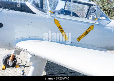 Detail of a vintage plane parked on cobblestones featuring bright yellow emergency markings Stock Photo
