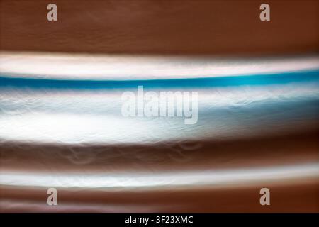 Abstract luminous horizontal light bands with cyan, white, and warm bronze tones creating a modern motion background. Stock Photo