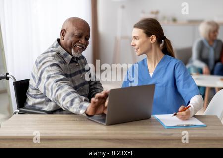 Happy African American Senior Man Interacting With Female Nurse In Healthcare Setting Stock Photo