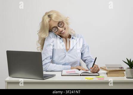 Happy Young Woman Talking On Phone And Taking Notes At Desk, Office Business Concept Stock Photo