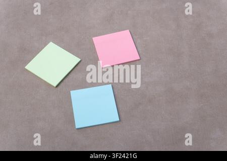 Three empty pastel sticky notes scattering on a neutral background, creating space for important messages and ideas Stock Photo