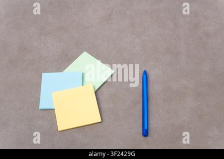 Sticky notes in various colors with a blue pen on a textured surface, representing study, organization, and communication Stock Photo