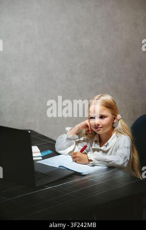 Child girl learning in online school using laptop homeschooling digital education platform class, kid writing studying primary grade course selfstudy Stock Photo