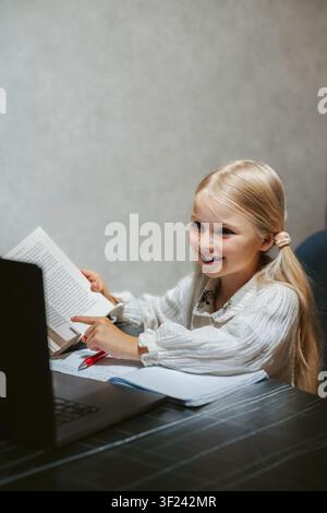 Child girl studying in online school platform using laptop homeschooling digital education class, smart kid reading book and learning course selfstudy Stock Photo