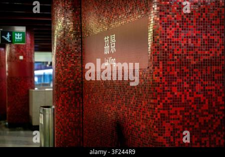 Close-up shot of a subway station pillar covered in red mosaic tiles, displaying "��" in white Chinese character and "Lai King" in English script Stock Photo