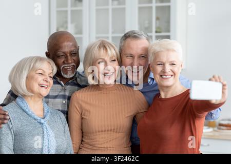 Five Happy Seniors Smiling Together Taking Selfie In Kitchen, Joyful Moment Stock Photo