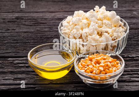 Composition of ingredients for making homemade popcorn, with corn kernels, sugar, oil, and ready-to-eat popcorn in a kitchen setting. Stock Photo