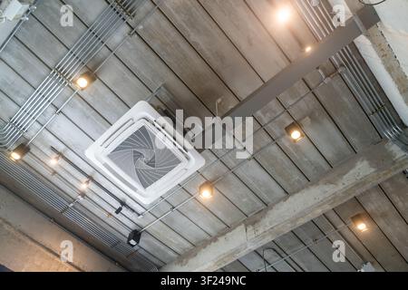 The image showcases a modern industrial interior ceiling featuring exposed concrete, metal pipes, and ductwork, complemented by installed lighting and Stock Photo