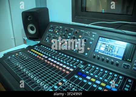 This image shows a modern electronic sound mixer with numerous controls, sliders, and buttons, alongside a computer interface and studio monitor speak Stock Photo