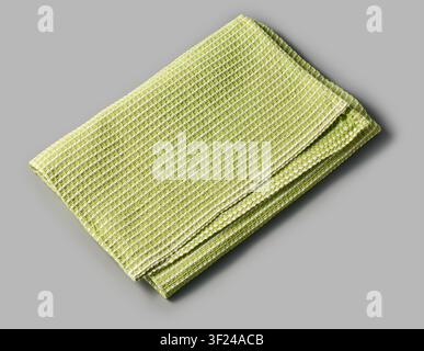 folded green dish towel isolated gray background, textured white striped pattern cleaning cloth, angle view Stock Photo