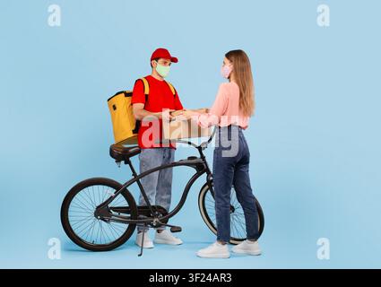 Delivery Man In Red Uniform Handing Package To Woman, Business Concept Stock Photo