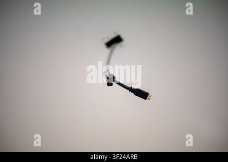 This image features a black USB cable with a Type-A connector suspended against a neutral white background, symbolizing technology, data transfer, and Stock Photo
