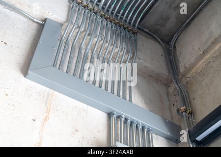 This image shows a close-up view of electrical conduit pipes and cables installed on a wall in an industrial or construction setting, demonstrating wi Stock Photo