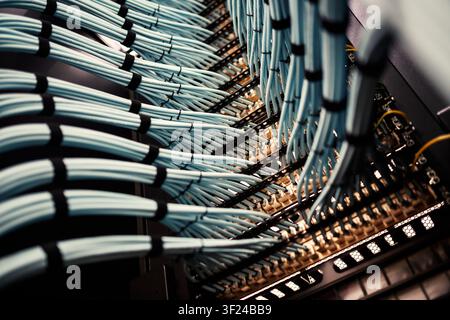 The image shows a detailed view of a data center with multiple server racks interconnected by numerous cables and wiring, highlighting modern IT infra Stock Photo