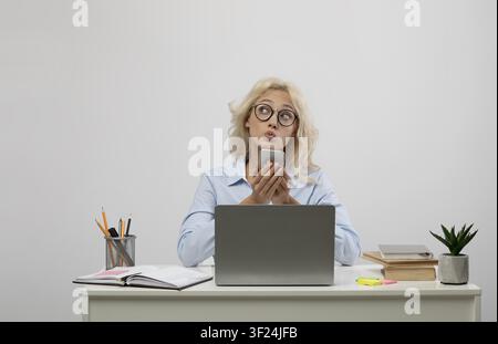 Thoughtful Young Caucasian Woman Using Smartphone While Working At Desk In Modern Office Stock Photo