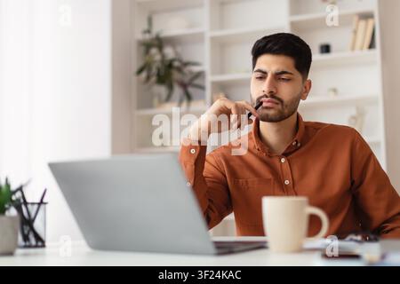 Focused Young Asian Man Working On Laptop In Modern Home Office, Business Concept Stock Photo