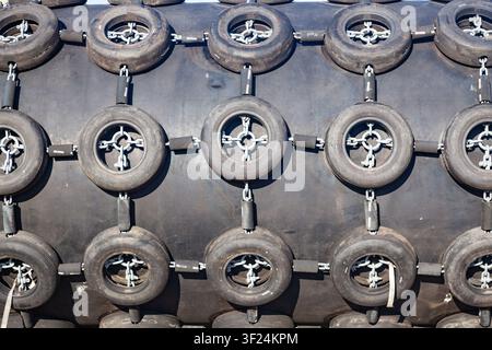 Full frame macro texture of a large black pneumatic rubber ship fender with a repeating pattern of chain tyre nets Stock Photo