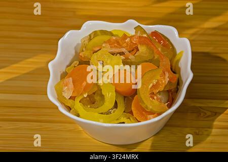 Cut pickled vegetables pile in ceramic bowl on table interior Stock Photo
