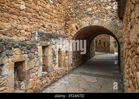 Medieval stone archway and narrow street in the historic old town of Pals, Baix Emporda, Girona, Catalonia, Spain. Stock Photo