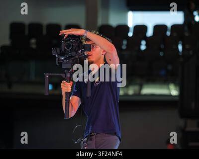 Professional videographer records a breaking competition using a camera mounted on a motorized gimbal. The image shows behind-the-scenes production du Stock Photo