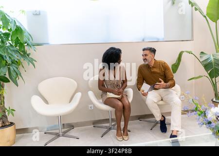 Diverse couple having an engaging conversation while waiting for a medical appointment Stock Photo