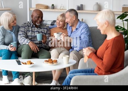 Happy Senior Diverse Group Of Friends Enjoying Coffee And Cookies At Home, Lifestyle Concept Stock Photo