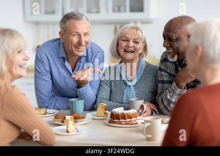 Happy Elderly Couples Enjoying Dessert Together In Bright Kitchen, Smiling And Laughing Stock Photo