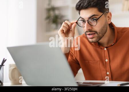 Surprised Young Man With Glasses Working On Laptop At Home, Office Concept Stock Photo