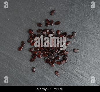 Watermelon Seeds on Black, Water Melon Black Seed Pile, Small Black Kernels, Raw Scattered Watermelon Seeds on Dark Stone Plate Background Stock Photo