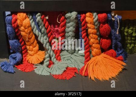 Colorful braided yarn cords and tassels displayed as textile craft samples. Bright fiber textures for handmade decoration, weaving, artisan design. Stock Photo