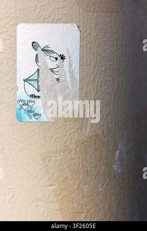 Tallinn, Estonia, August 31, 2024: Weathered sticker depicting Little My, a character from the Moomins, pasted on a rough beige wall Stock Photo