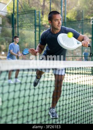 Paddle tennis player performing left-handed backhand on outdoor court Stock Photo