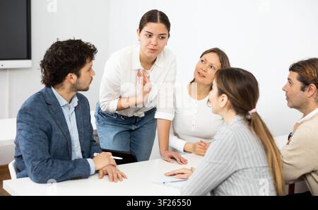 Colleagues sharing ideas and points of view, listening to each other while sitting around desk after advanced training course Stock Photo