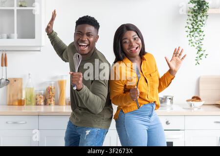 Happy African American Couple Dancing And Cooking In Modern Kitchen, Joyful Lifestyle Stock Photo
