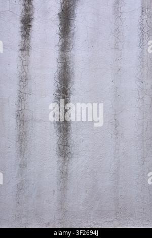 Old white stucco wall texture with vertical water stains and cracks Stock Photo